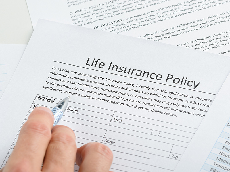 hand with pen filling life insurance policy documents houston tx